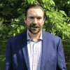 Headshot of a man with greenery in the background