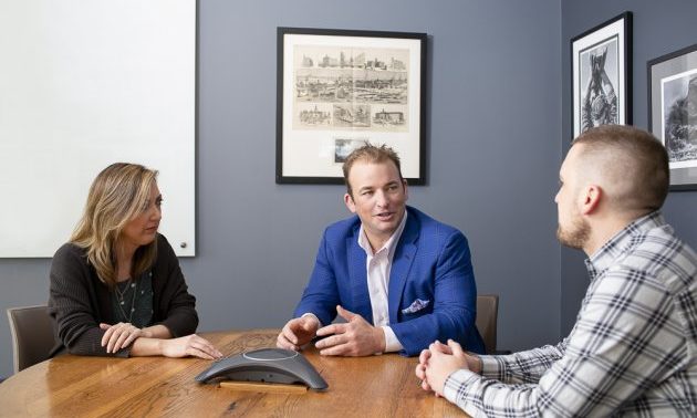 Three people sitting around a table with a speaker in the middle