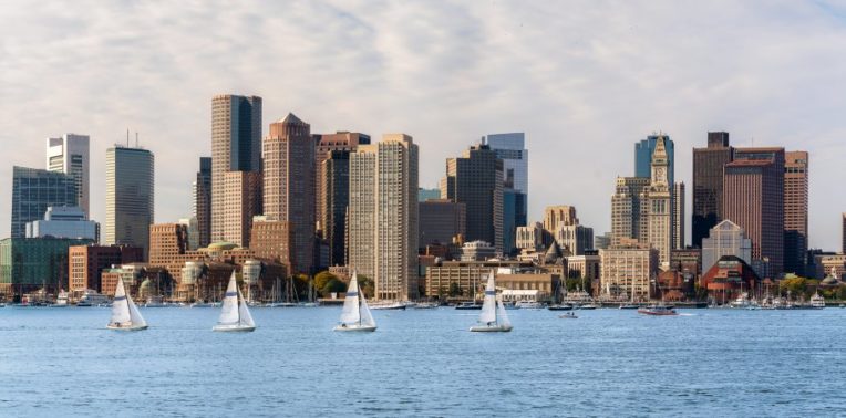 City skyline overlooking water with multiple sailboats