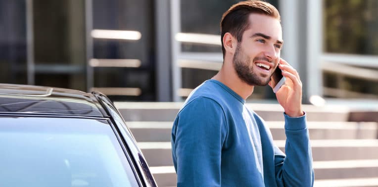 Man talking on a cell phone next to a car