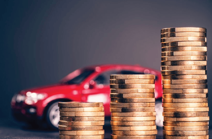 Increasingly tall stacks of coins with a red car in the background