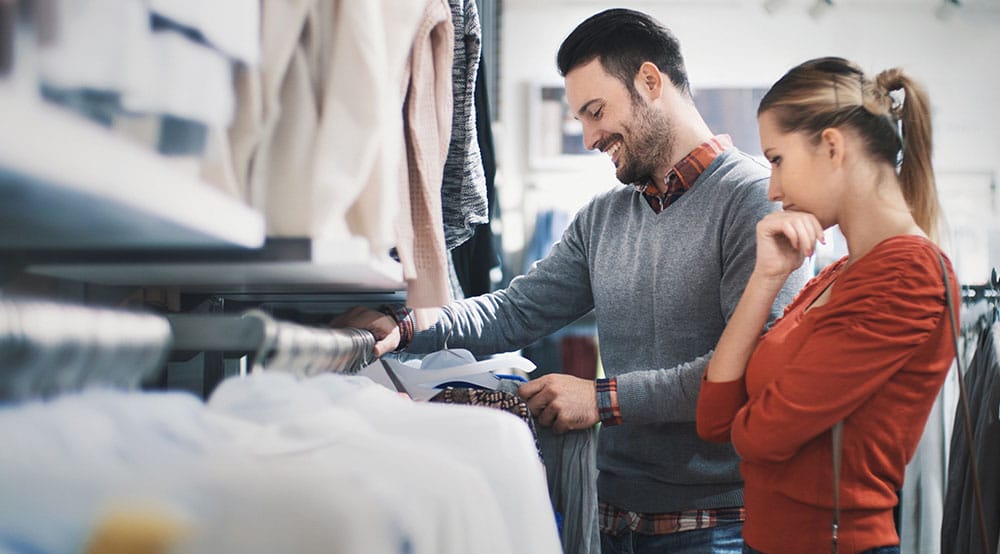 Two people browsing a rack of clothing