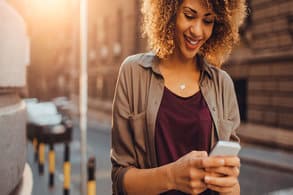 Woman walking down a street looking at a cell phone