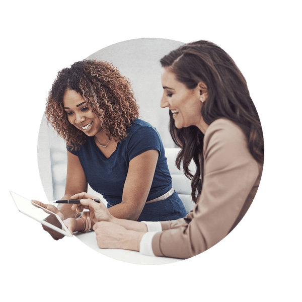 Two women looking at a tablet screen while one points with a pen