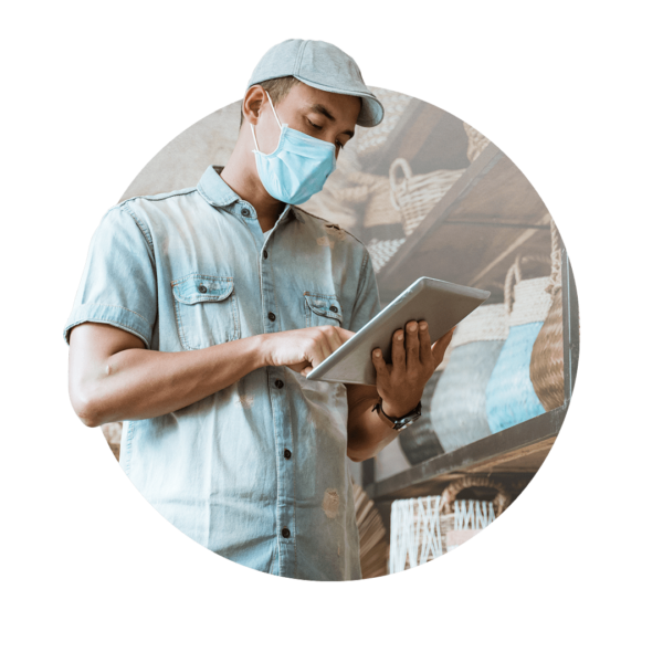 Man with a hat and face mask looking at a tablet