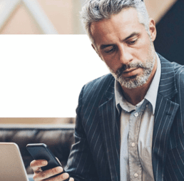 Man with a beard looks away from the cell phone in his hand