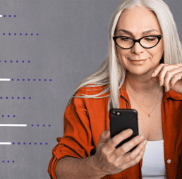 Woman with glasses looking down at a cell phone in her hand