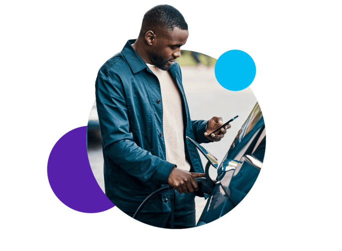 Man filling a car with gas while looking at a cell phone