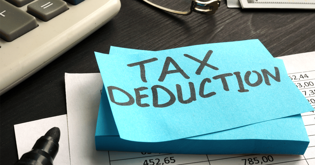 cluttered desk with sticky note saying "tax deduction" evoking the question is mileage tax deductible?