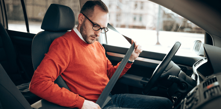 man buckles seatbelt evoking Corporate Driver Safety Training