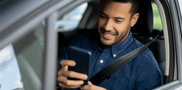 man in car using phone evoking IRS Approved Mileage Logs