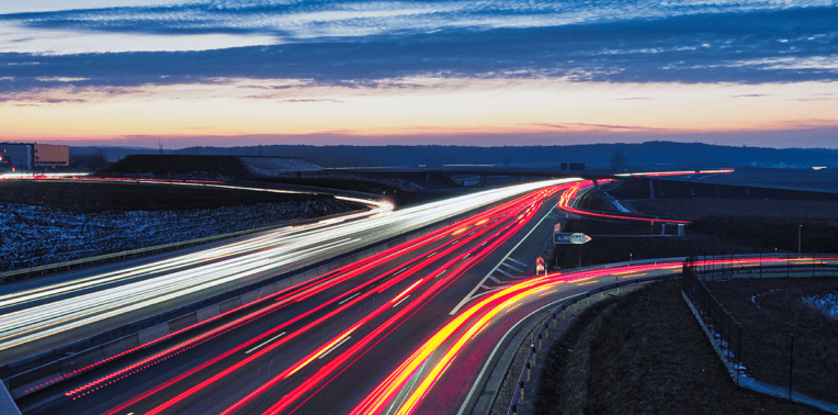 long exposure image of vehicle lights on a highway evoking federal mileage allowance