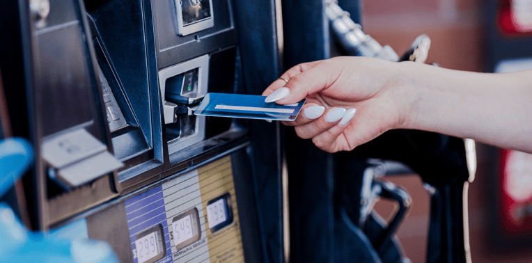 woman paying for fuel at a fuel pump with a credit card evoking the question how much do fuel cards cost?