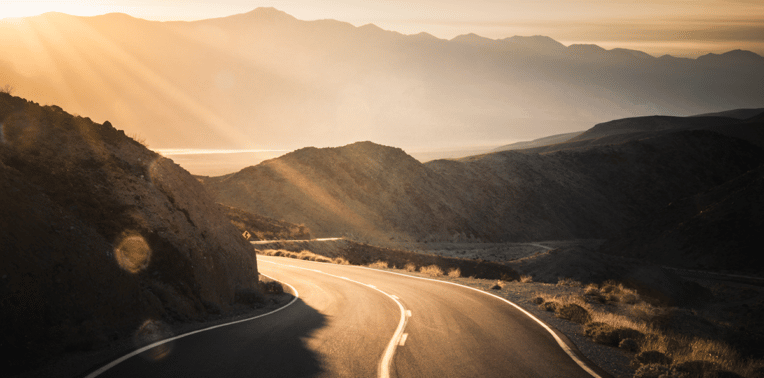 image of a mountain road during sunrise evoking 2023 IRS standard mileage rate
