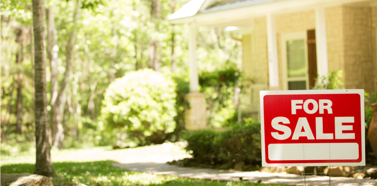 image of home with for sale sign set in front lawn, evoking Increased Mortgage Interest Rates