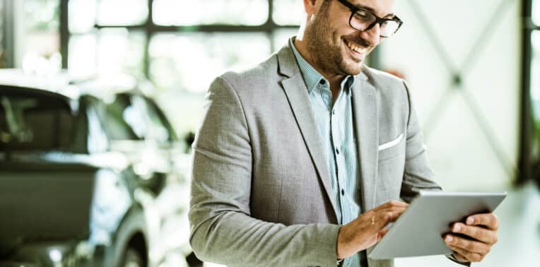 image of man reviewing ipad with car in background evoking fleet management companies