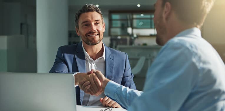 image of business men shaking hands before a computer evoking business insights