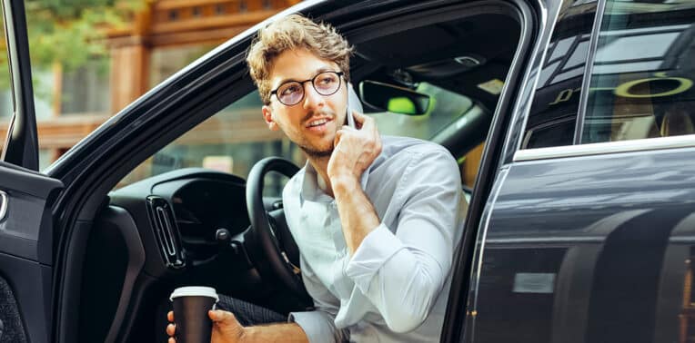 business man with coffee and phone leaving car evoking Motus perks