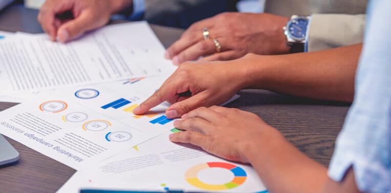 business people at table of charts and graphs of data evoking core-flex policies