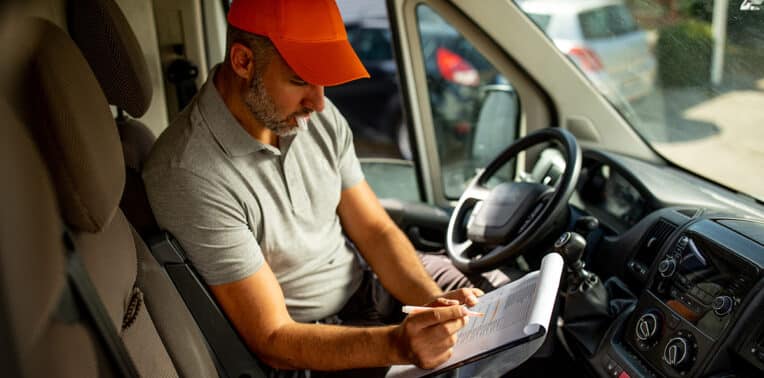 man with notepad in van evoking reimbursing temporary drivers