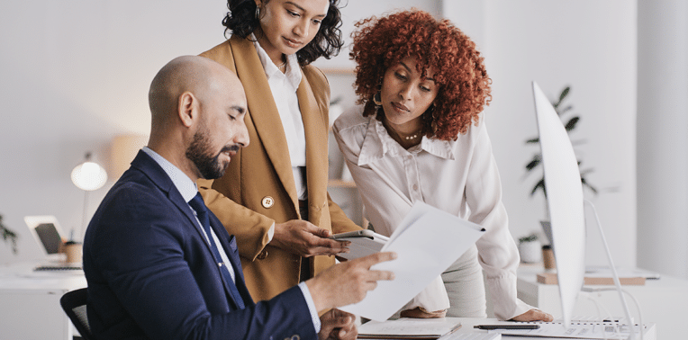 image of business people around a piece of paper evoking Compliance in Vehicle Reimbursement Programs